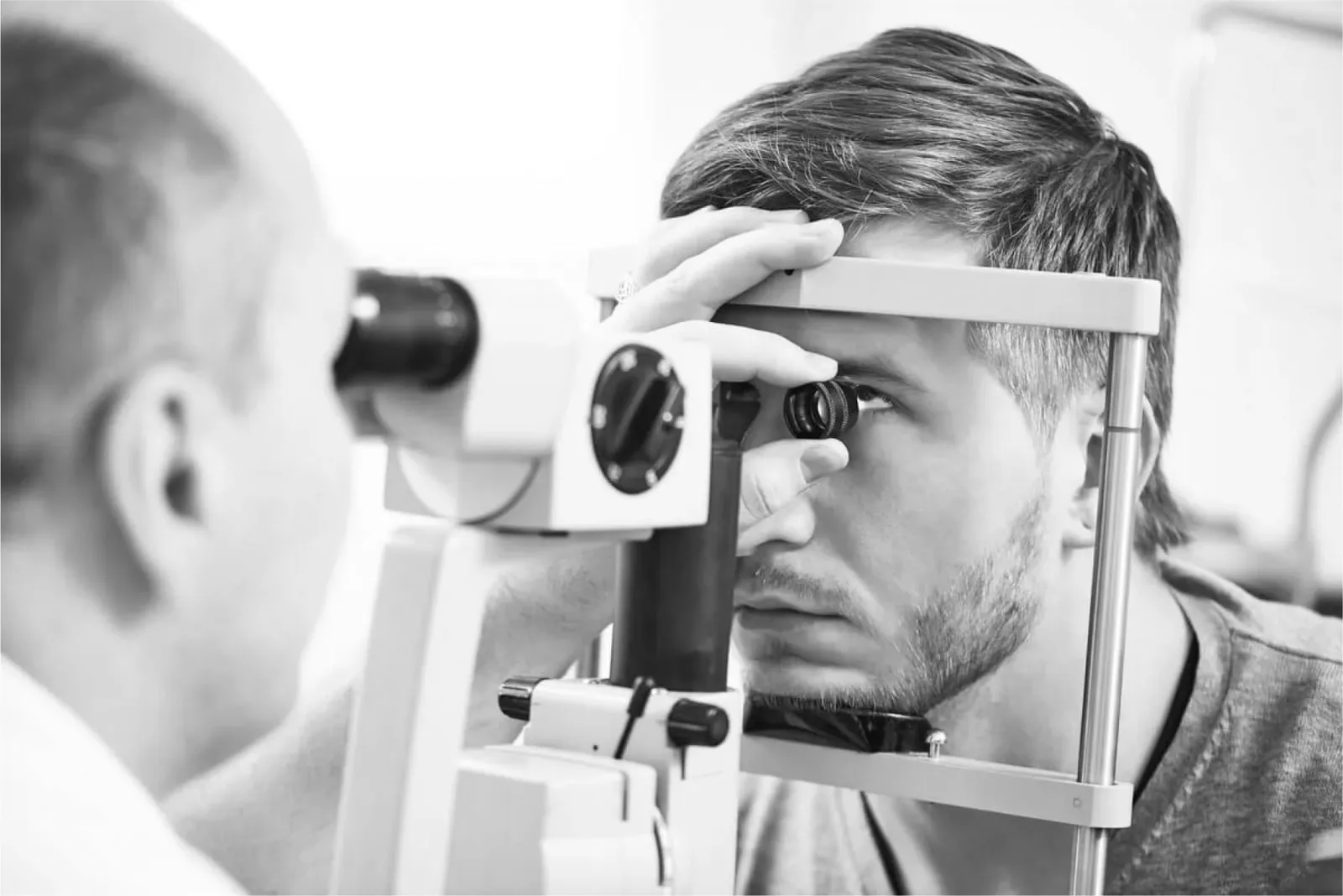 Oftalmólogo observando el interior del ojo de un paciente apoyado en la lámpara de hendidura