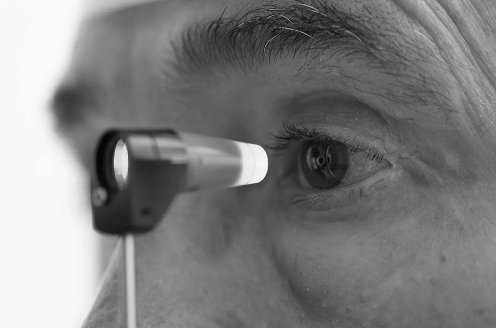 Tonómetro con luz azul acercándose al ojo de un paciente para medir la presión ocular